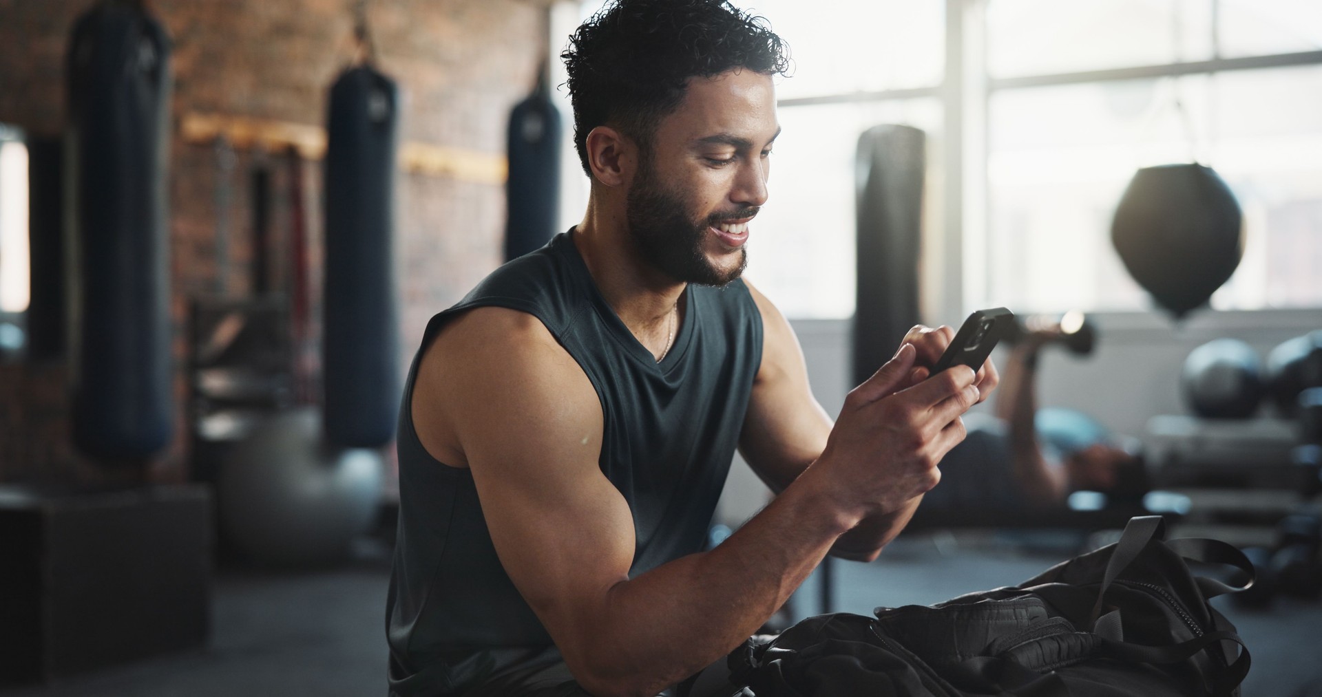 Fitness, gym and man with phone on break for social media, internet and online message. Athlete, happy and person rest with smartphone for mobile app for exercise, training and workout progress